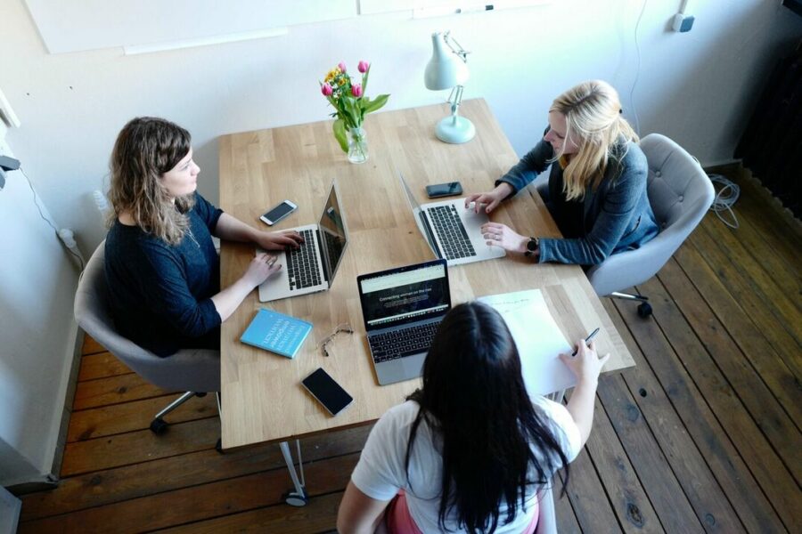 Trois femmes travaillent autour d'une table à roulettes avec leur PC portables