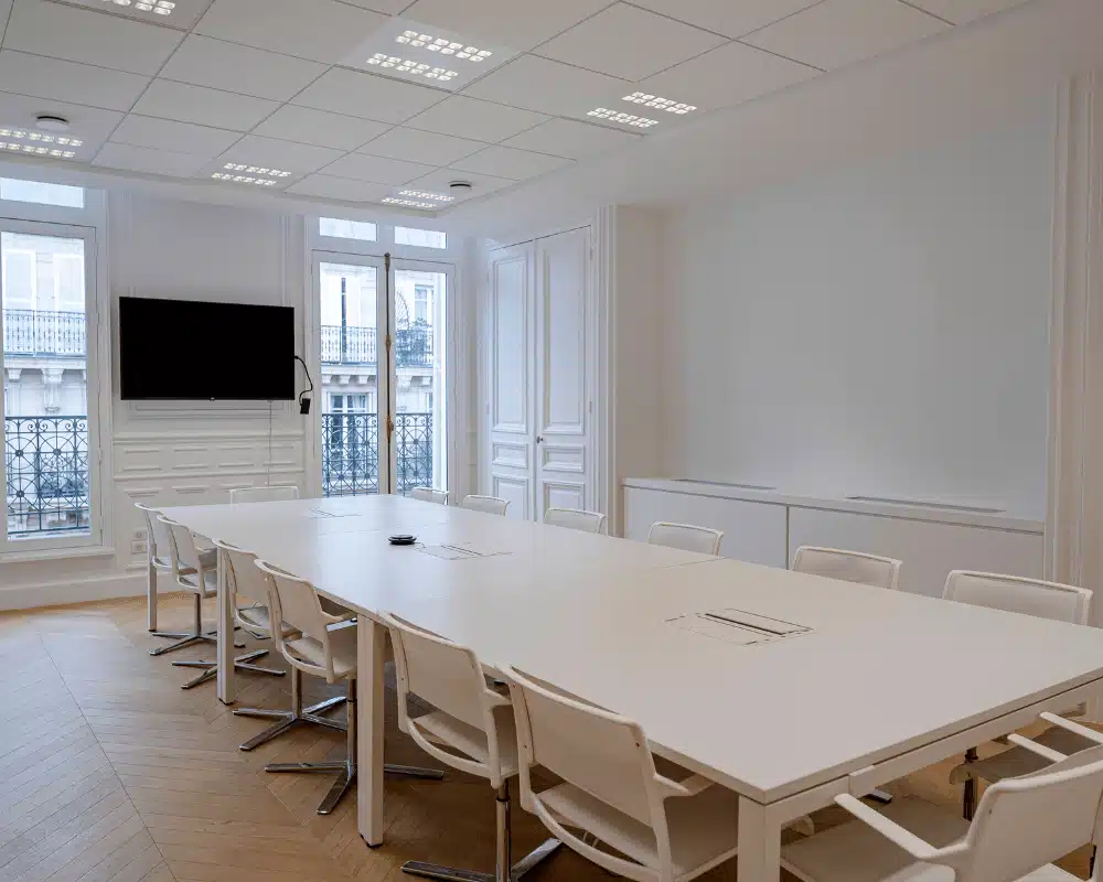 Salle de réunion parisienne épurée avec grande table et téléviseur pour présentations dans cabinet d'avocat