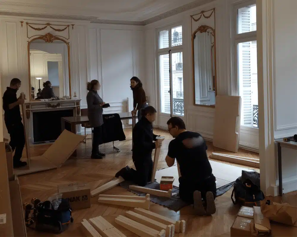 Équipe de déménagement assemblant des meubles dans un bureau à Paris