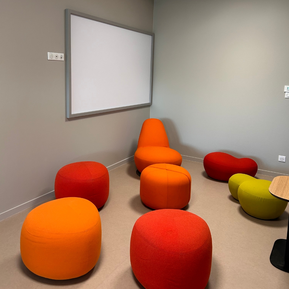 Une creative room avec des poufs et un tableau blanc